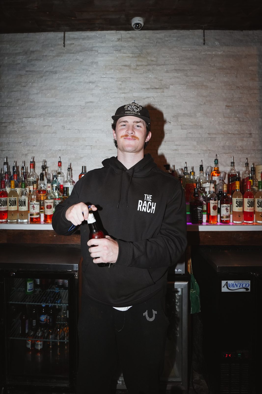A Whiskey Ranch bartender opening a bottle